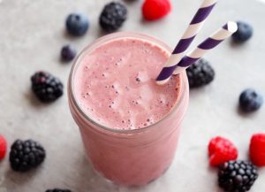 photo of triple berry smoothie in glass with two straws